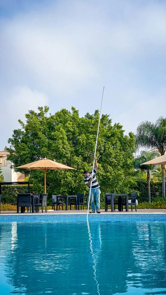 Pool professional skimming a residential pool