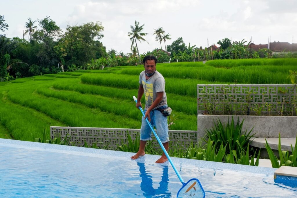Pool technician cleaning a residential swimming pool in Irvine with a telescopic pole