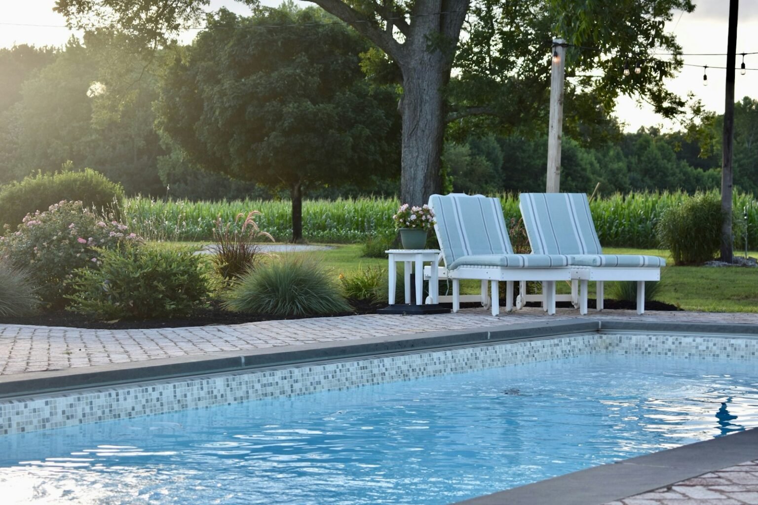Poolside lounge chairs beside a clean, well-maintained residential pool