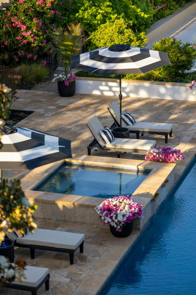 Poolside spa with lounge chairs and flowering planters