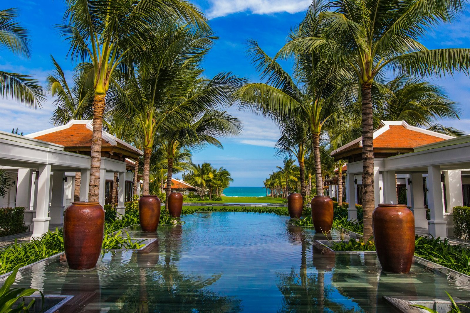 Resort-style backyard pool with decorative urn water features and palms